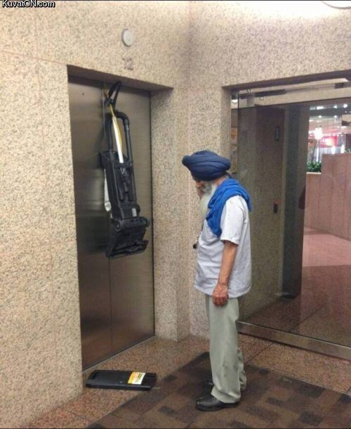 Photo d'un homme ayant son aspirateur coincé dans un ascenseur